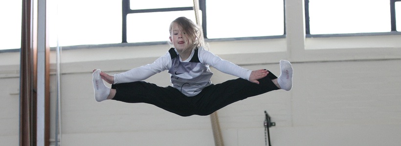 Young girl performing a jump on a trampoline