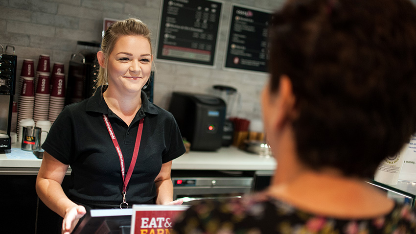 Female Costa staff member serving behind the counter at Cardiff Met