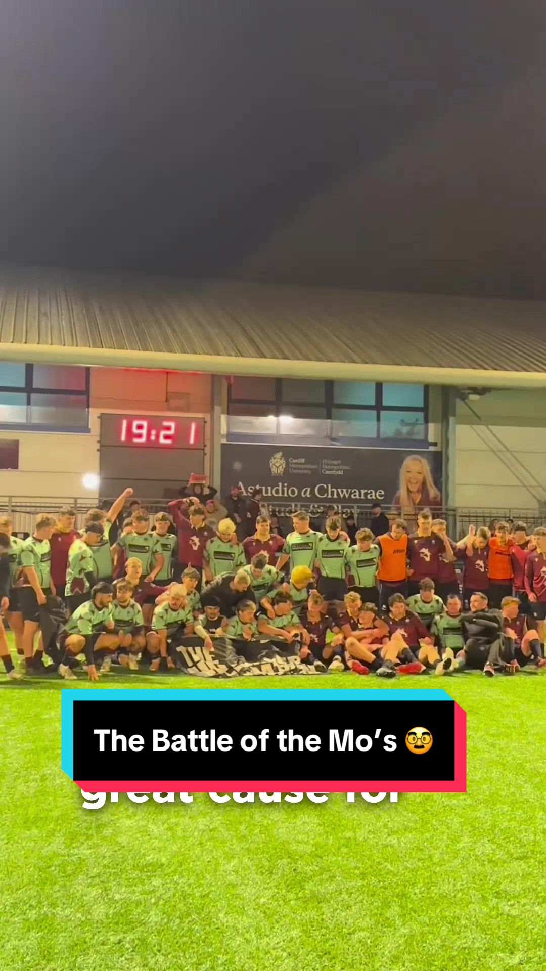 A large group of rugby players pose for a photograph on a sports field