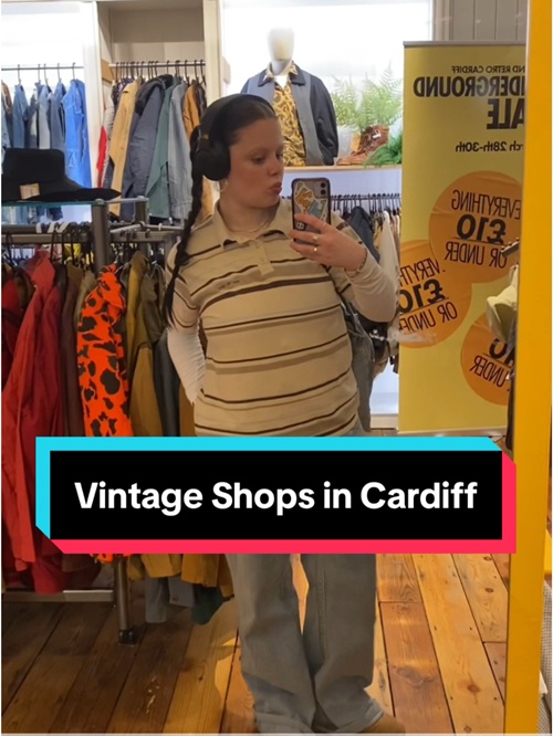 A young woman poses for a picture in the mirror of a vintage clothes shop