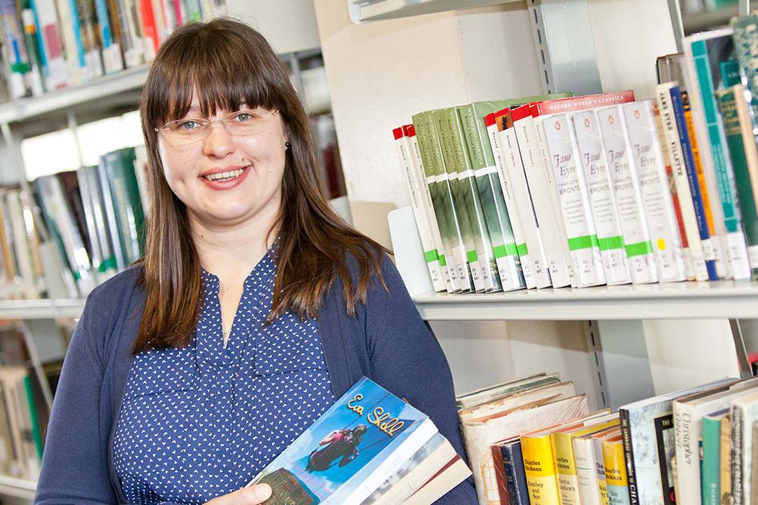 A person stands in front of bookshelves in a library.