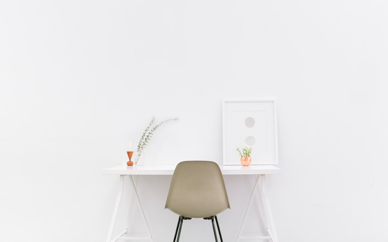 An empty workspace with a chair, desk and plants arangaed