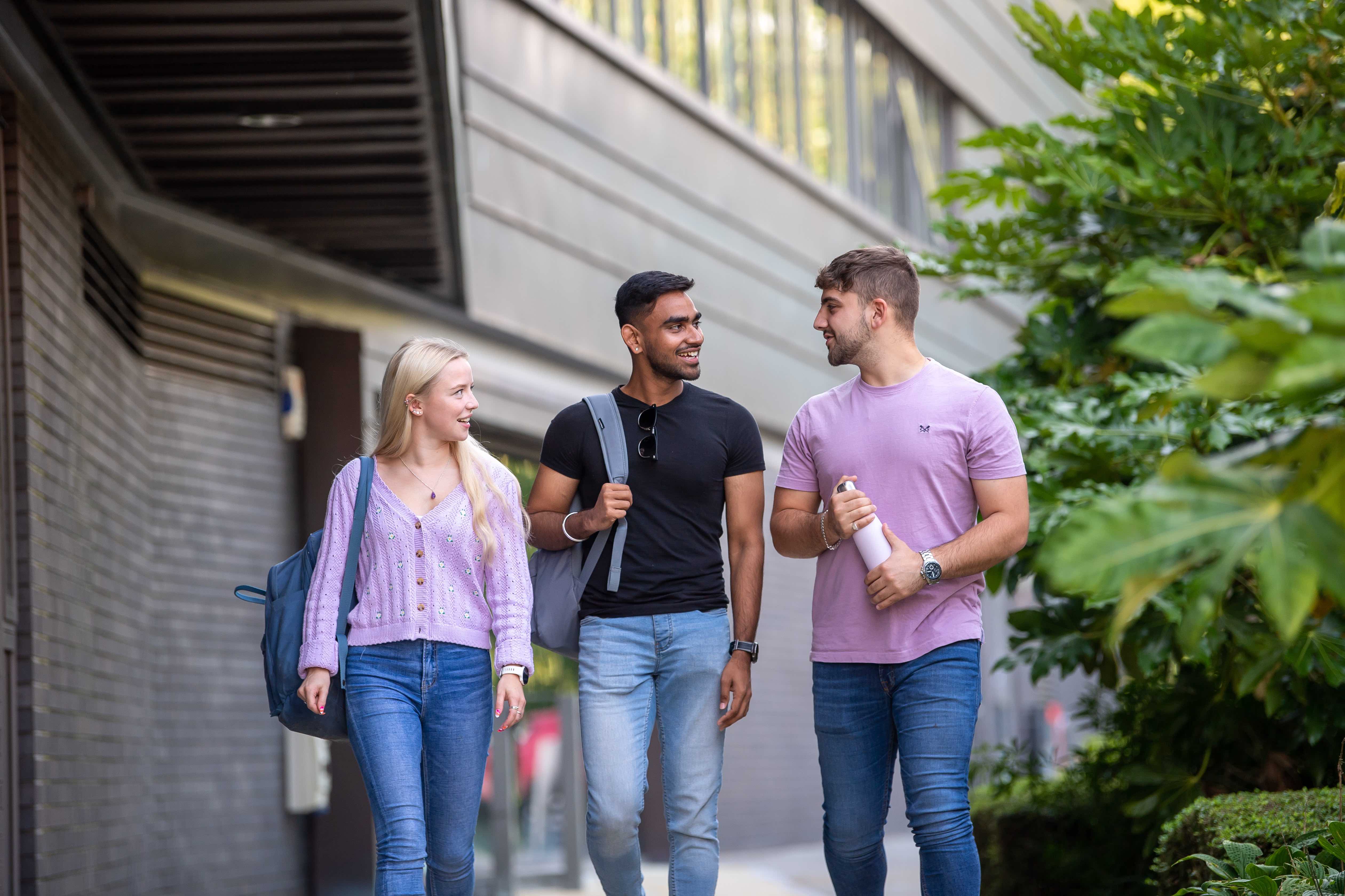 Three students walking outdoors, on-campus