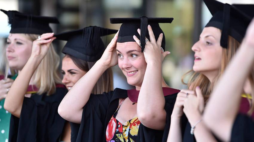 Graduation student in gown adjusting cap